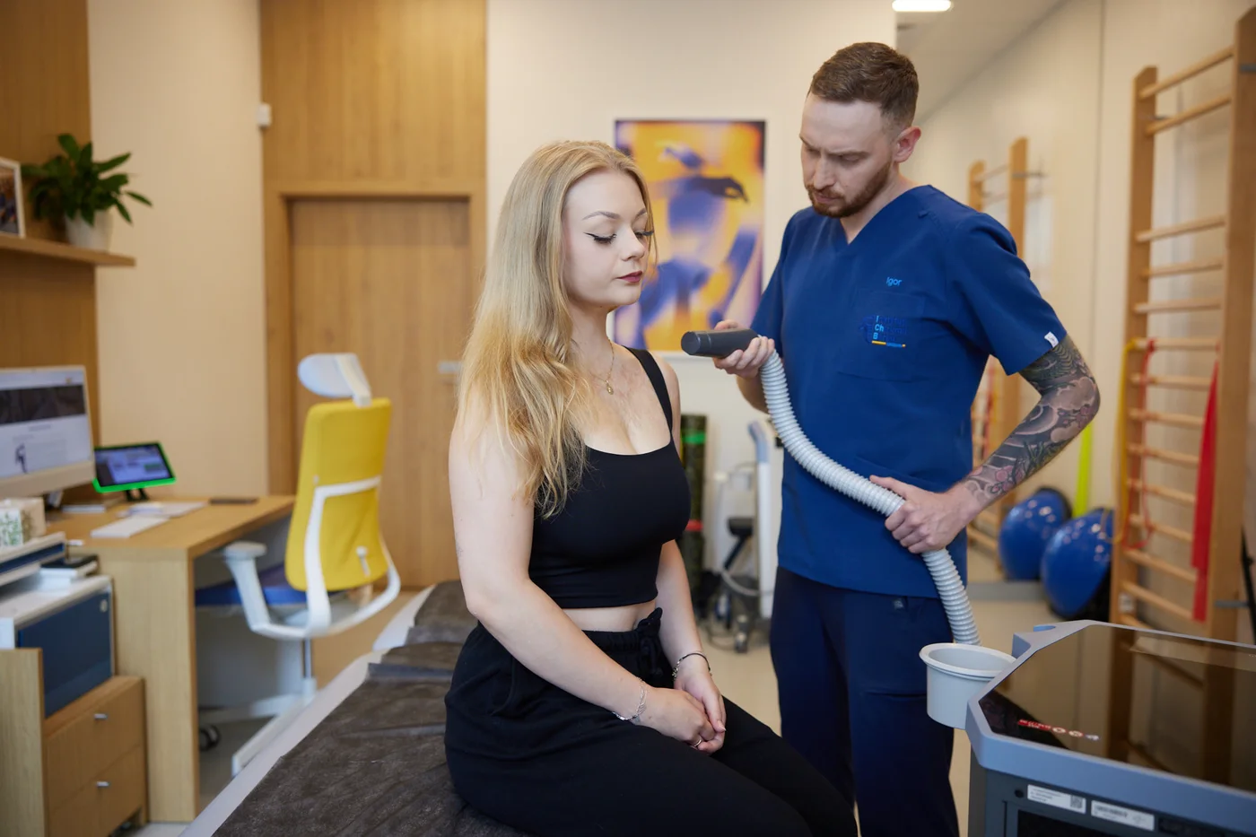 Fizjoterapeuta prowadzi zabieg na barku pacjentki w sali rehabilitacji